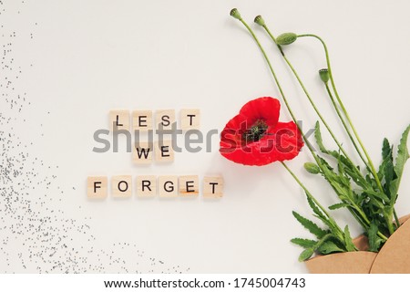 Red poppy flowers in envelope on white background. Wooden alphabet text Lest we forget. Remembrance day, Veterans day, Anzac day, lest we forget, Memorial Day concept