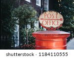 Red post box with a retro Post Office directional sign on top in London, UK.