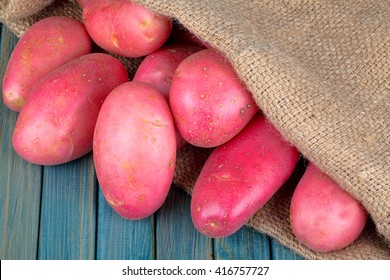 red potatoes in burlap sack on a blue wooden table