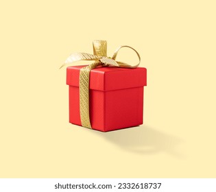 Red present box with gold ribbon on a yellow background. Gift concept for a birthday, wedding or new year. Copy space. - Shutterstock ID 2332618737