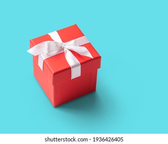  red present box with white ribbon on  blue background. Concept and celebration photo. Copy space