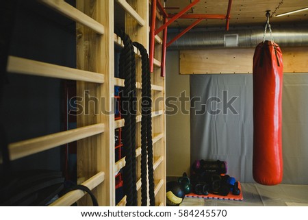 Red Punching Bag and Sports Equipment for Training in Modern Boxing Gym. Beautiful Toned Sport Background