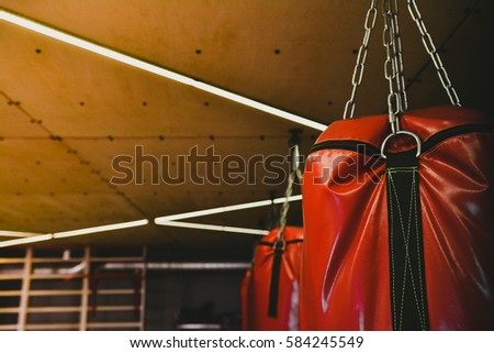 Red Punching Bags for Training Power Punch in Modern Boxing Gym. Beautiful Toned Sport Background with Copy Space