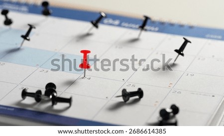 Red push pin marking an important date. Appointment reminder and planning concept.