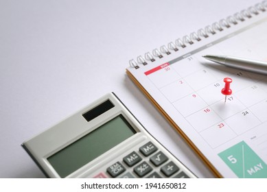 Red Push Pin On May 17 Calendar With Pen And Calculator On Top Of Table. Reminder Of New Tax Day For 2021.