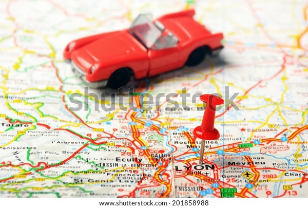 Red\
push pin pointing at Lyon , France  map   and a\
car