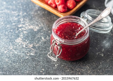 Red Rasberries Jam In Jar On Black Table.