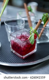 Red Raspberry Drink With Icecube Decoration With Cinnamon Stick,mint Leaves And Fresh Raspberry On The Tray And Empty Glasses