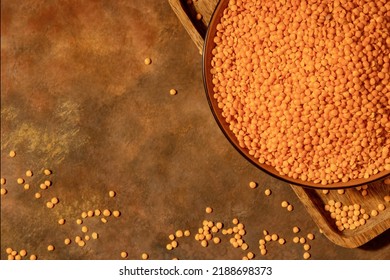 Red Raw Grits Lentils On A Plate Close-up On Top On A Brown Background