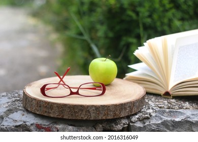 Red reading glasses, green apple and open book. Selective focus. - Powered by Shutterstock