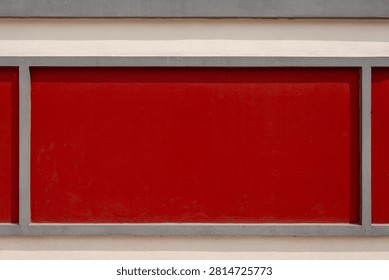 Red rectangular wall panel framed by grey concrete borders on a building exterior.