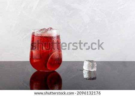 Red refreshing drink with ice or fruit iced tea. Lemonade with hibiscus and passion fruit. Grey background, copy space.