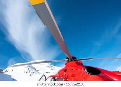 a red rescue helicopter stands on the snow-covered mountains of the Austrian Alps - Powered by Shutterstock