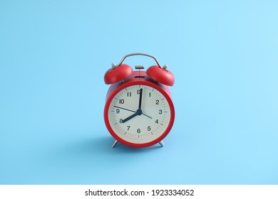 Red retro alarm clock isolated on a blue background
