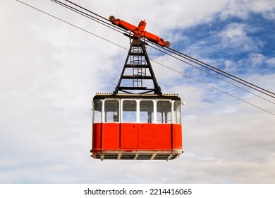 Red retro cabin of the cable car against the background of white clouds
