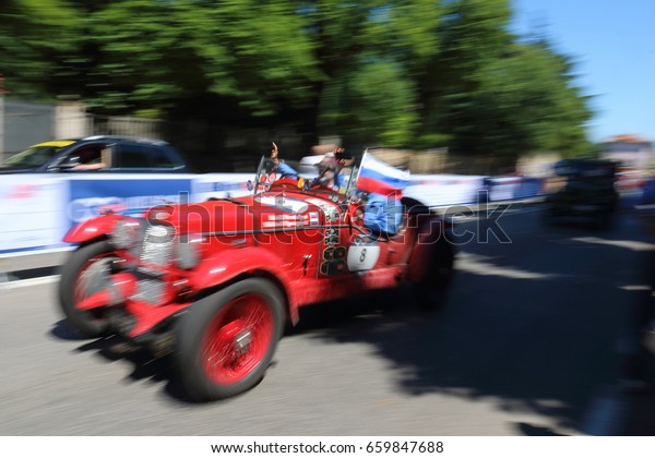Red retro car with two pilots and Russian flag at\
speed. Finish event 1000 Miles Annual race of retro auto. Brescia\
Italy May 21 2017