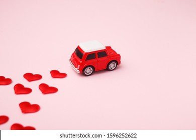 Red retro toy red car with red bow for Valentine's day on pink background with heart confetti. - Powered by Shutterstock