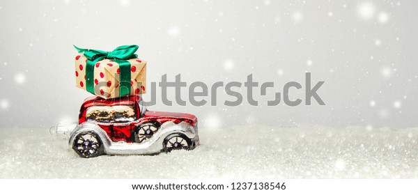 Red retro toy car delivering Christmas or New\
Year gifts on festive\
background