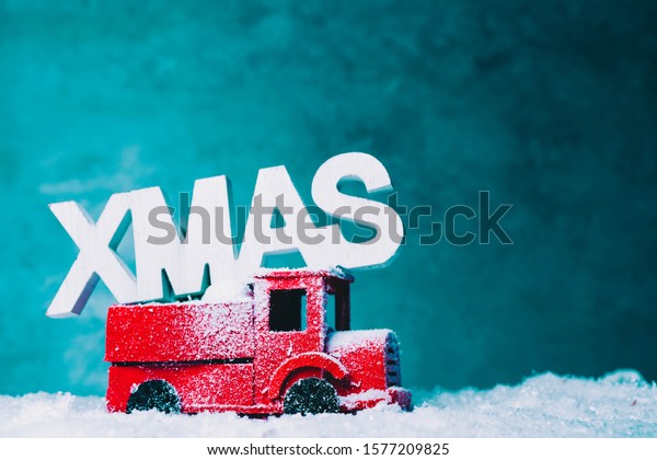 Red retro toy car\
transporting  Christmas tree, on a snowy road, christmas concept\
for holiday travel.