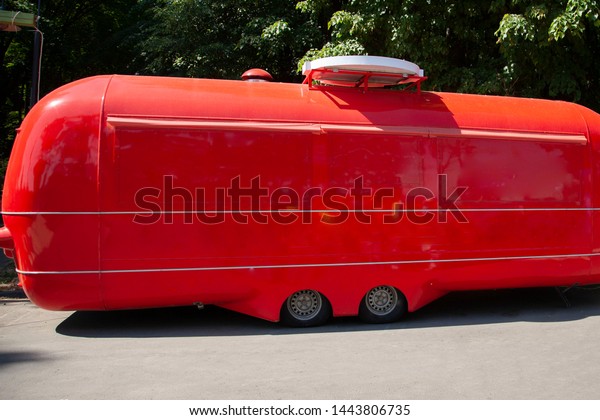Red retro van. Shop on\
wheels. House on wheels . Trade in the city park. Trailer for\
transportation.