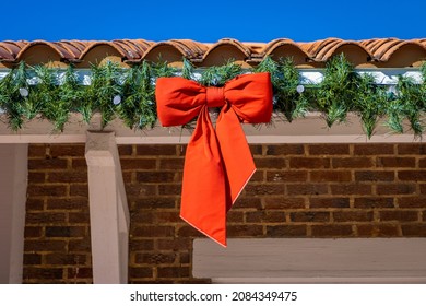 Red ribbon bow and wreath hanging from building roof