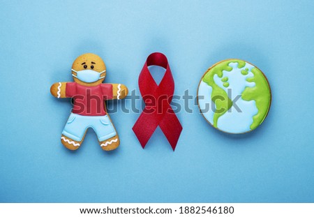 red ribbon and gingerbread boy and planet earth on blue background. world day of fight against cancer. men's health