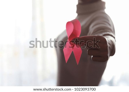 The red ribbon of the girl. The girl is holding a red ribbon. Health concept red ribbon. Breast cancer.