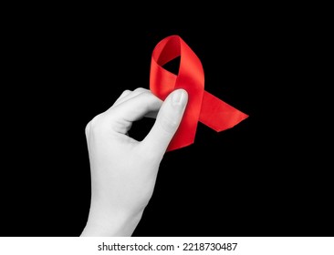 Red Ribbon In Hand On Black Background For HIV AIDS Awareness Day, 1 December. High Quality Photo