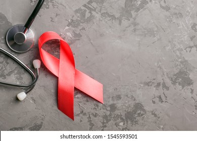 red ribbon and stethoscope on a concrete background. 1 December World AIDS Day, HIV illness campaign. Copy space for text