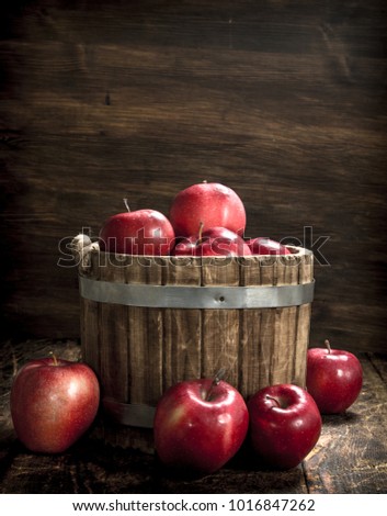 Red ripe apples in a wooden bucket. On a wooden background.
