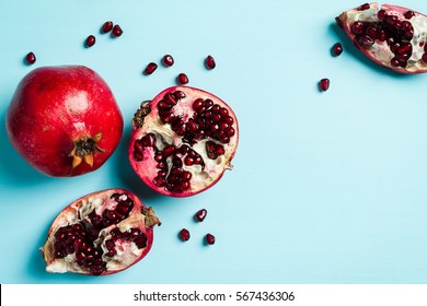 Red ripe pomegranates on blue background, copy space, top view.