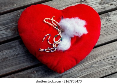 red ripped stuffed heart with jewelry lying on floor