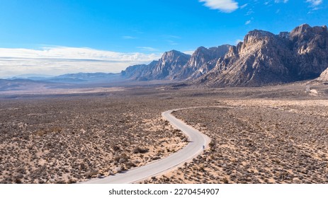 Red Rock Canyon in Las Vegas Nevada shows a lone, remote road along the vibrant mountainside where hiking activity is common and conservationists strive to maintain a true conservancy.


