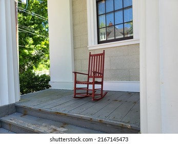 A Red Rocking Chair Sitting On A Deck.