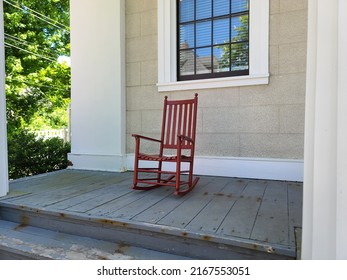 A Red Rocking Chair Sitting On A Deck.