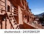 Red rocks of Manitou Springs cliff dwellings.  Natural adobe walls with stone and brick showing.  Native American ancestral structure with ladders shown.   