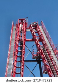Red roller coaster track loop against a bright blue sky