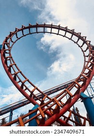Red roller coaster under a clear blue sky.