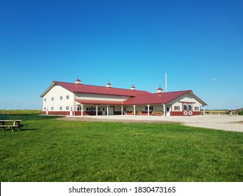 Red roof barn on the farm, with a bright blue sky in the background and lush green grass in the front