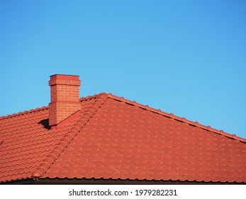 Red Roof Tiles With Red Brick Chimney On Blue Sky Background.