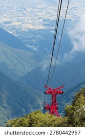 The red ropeway support pillars and the cityscape below seen from the summit