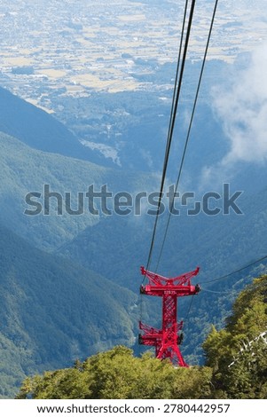 The red ropeway support pillars and the cityscape below seen from the summit