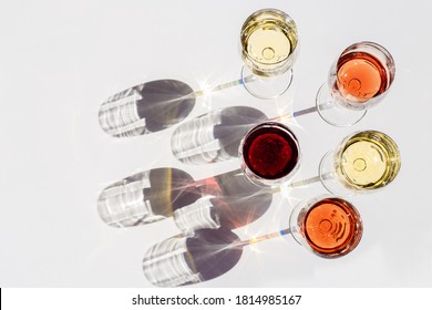Red, rose and white wine top view in sunlight. Assorted wine in glass on white table. Dark shadows. Bar, winery, wine degustation concept.