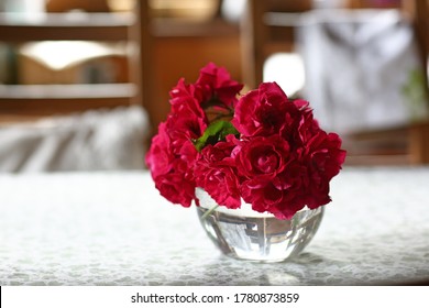 red roses in crystal vase on white table on kitchen interior close up photo 