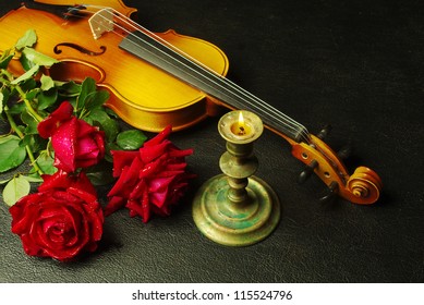 Red roses, violin, candle.Black background