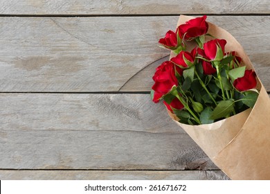 Red roses wrapped in paper on wooden table background - Powered by Shutterstock