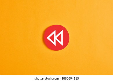 Red Round Circle With A Rewind Button Against Yellow Background.