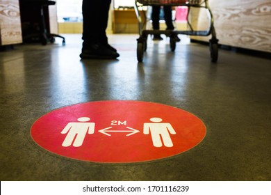 Red round sign printed on ground at supermarket cash desk register informing people to keep 2 meter 6 feet distance from each other,prevent spreading Coronavirus COVID-19 virus disease infection,UKUS - Shutterstock ID 1701116239