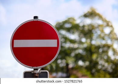 A red round sign warns: entrance forbidden. It is a one way street. In the background a tree, out of focus with beautiful bokeh.
