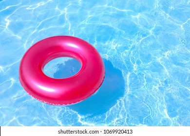 Red Rubber Ring Float In A Refreshing Blue Swimming Pool.